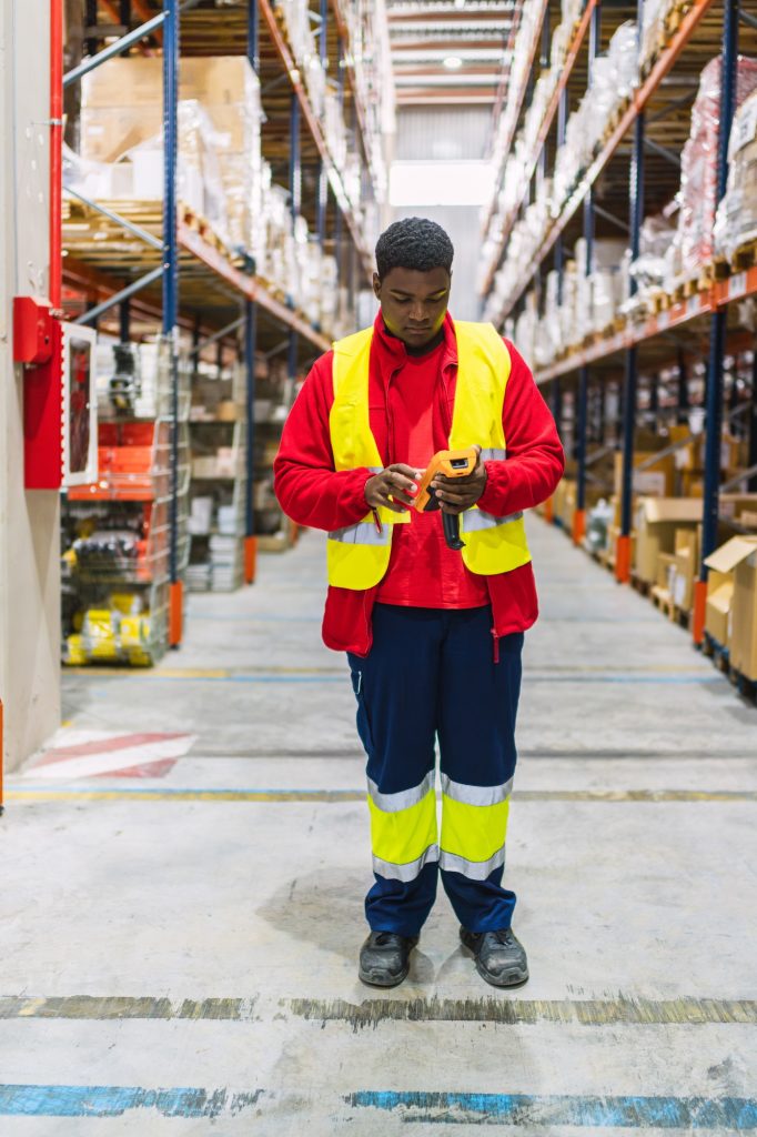 Warehouse worker scanning packages with barcode scanner in logistics center